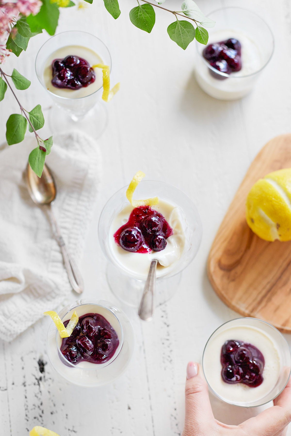 woman picking up a dish of blueberry lemon panna cotta