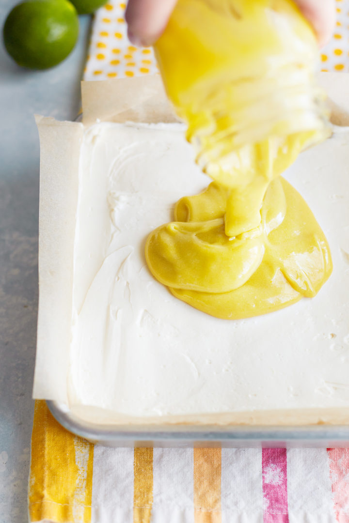 woman adding lime curd on top of the no bake cheesecake bars