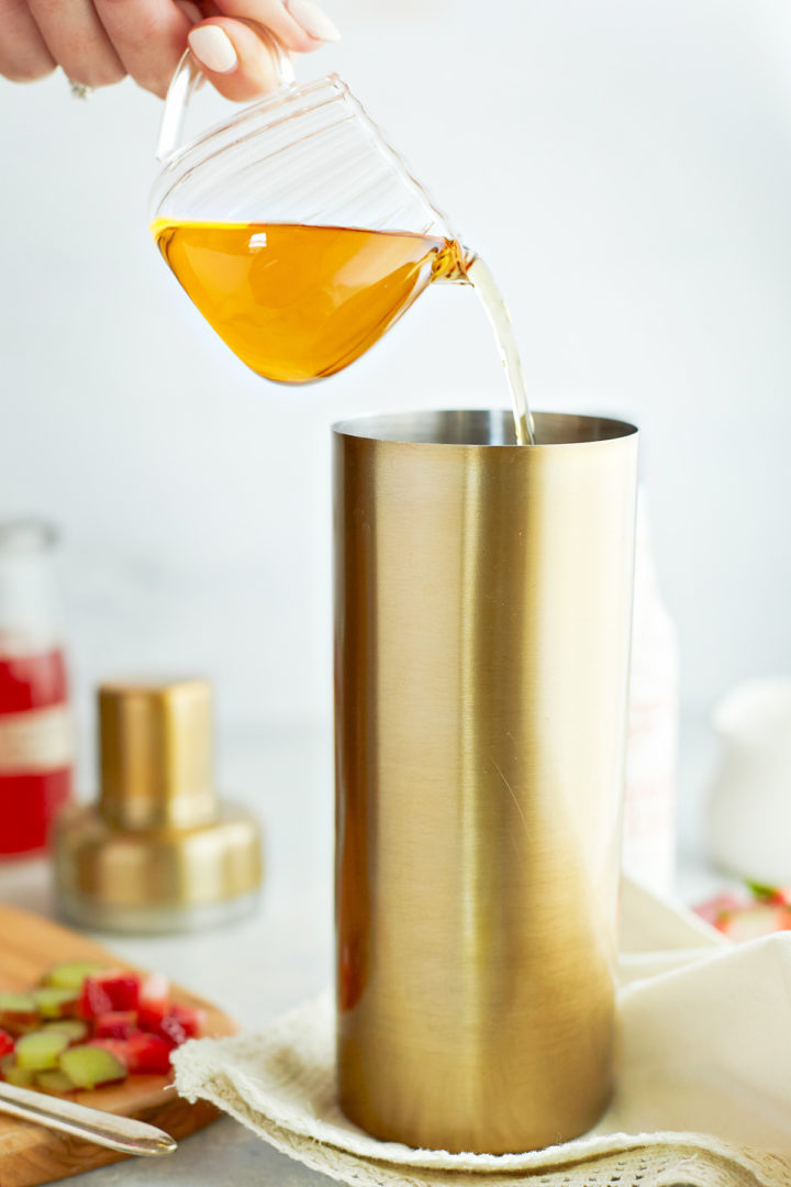 woman adding whiskey to a cocktail shaker for a summer whiskey cocktail recipe