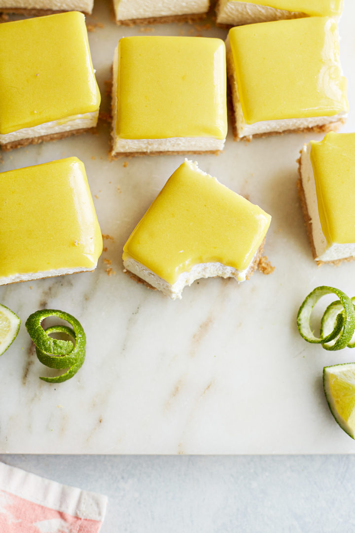 no bake lime cheesecake bars on a marble board, one of the bars has a bite out of it