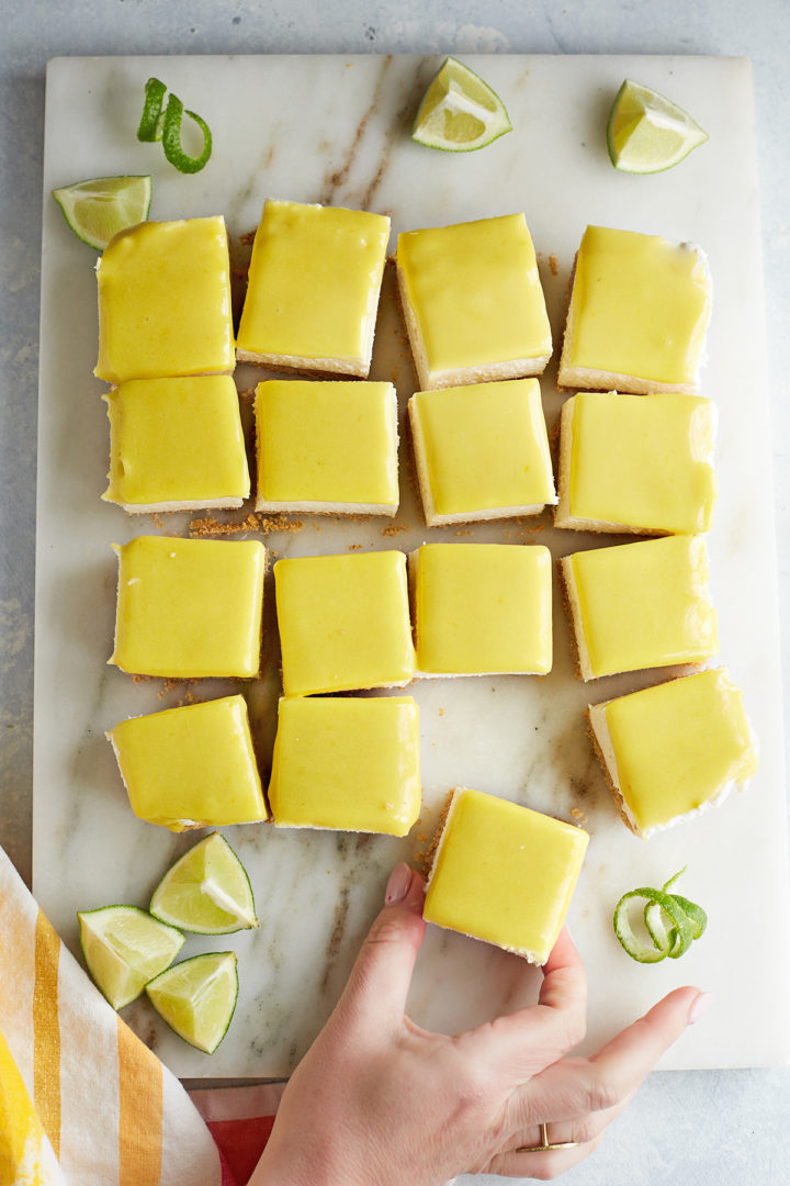 woman picking up a square of cream cheese  lime bars