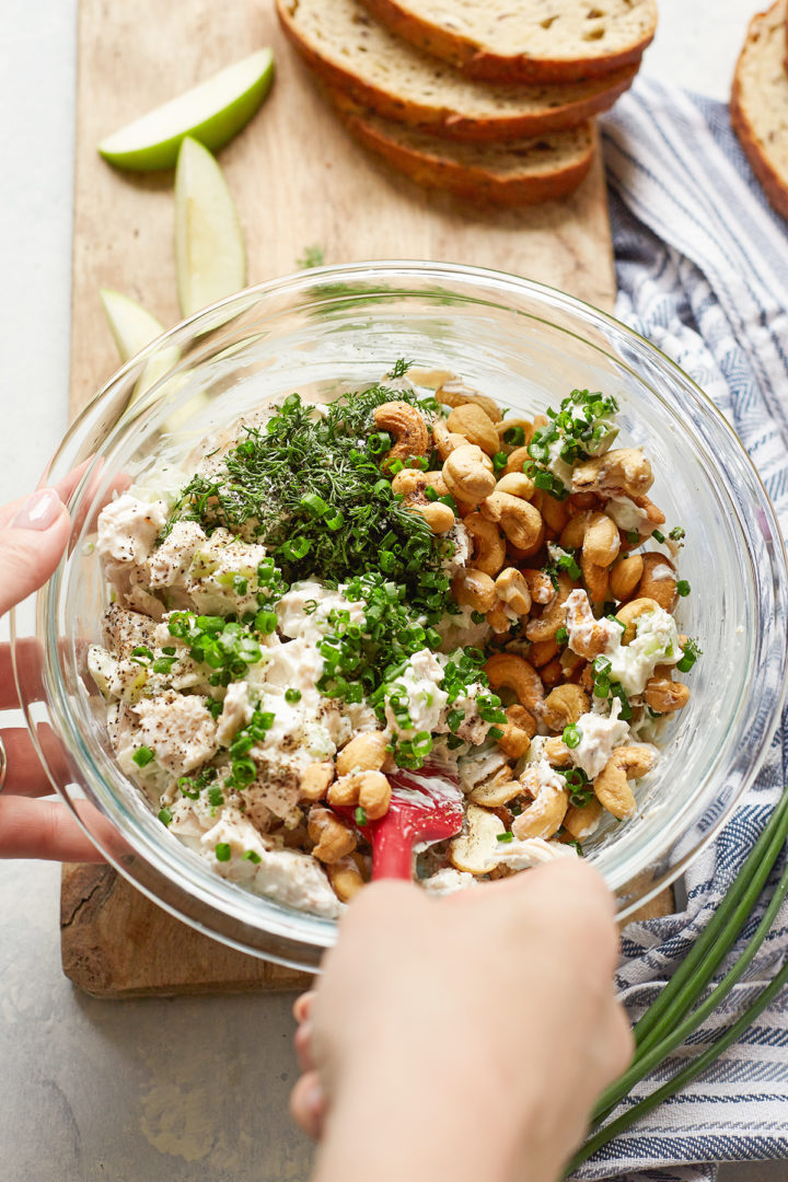 woman stirring a bowl of ingredients to make chicken salad with yogurt