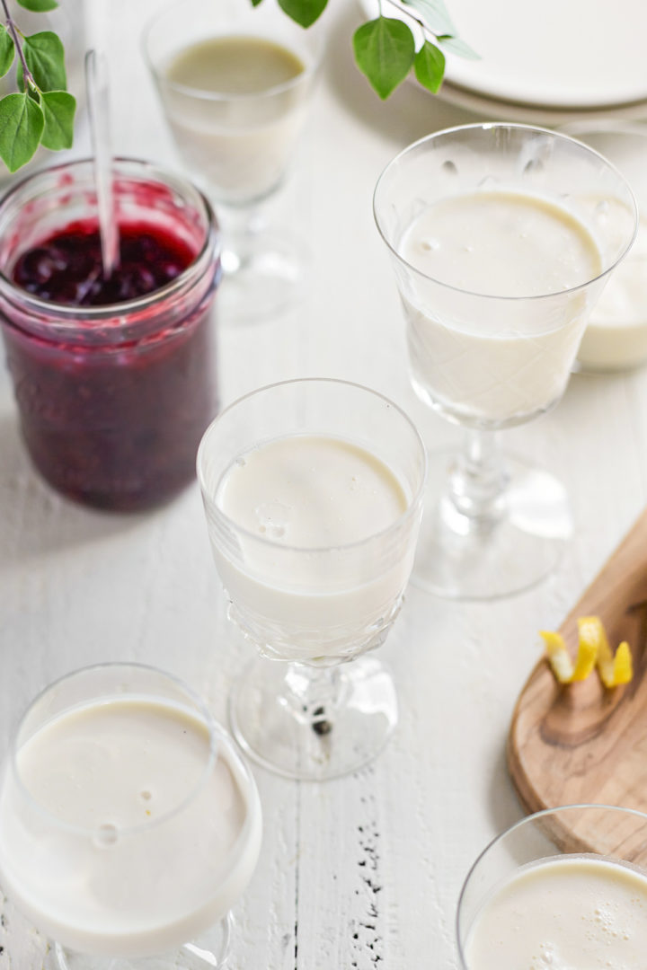 lemon panna cotta in dessert dishes next to a jar of blueberry sauce