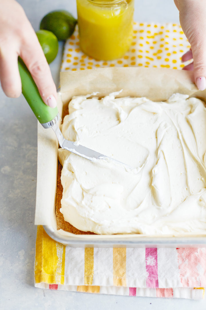 woman spreading no bake cheesecake filling into a graham cracker crust