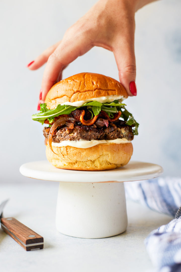 woman putting a bun on a blue cheese burger