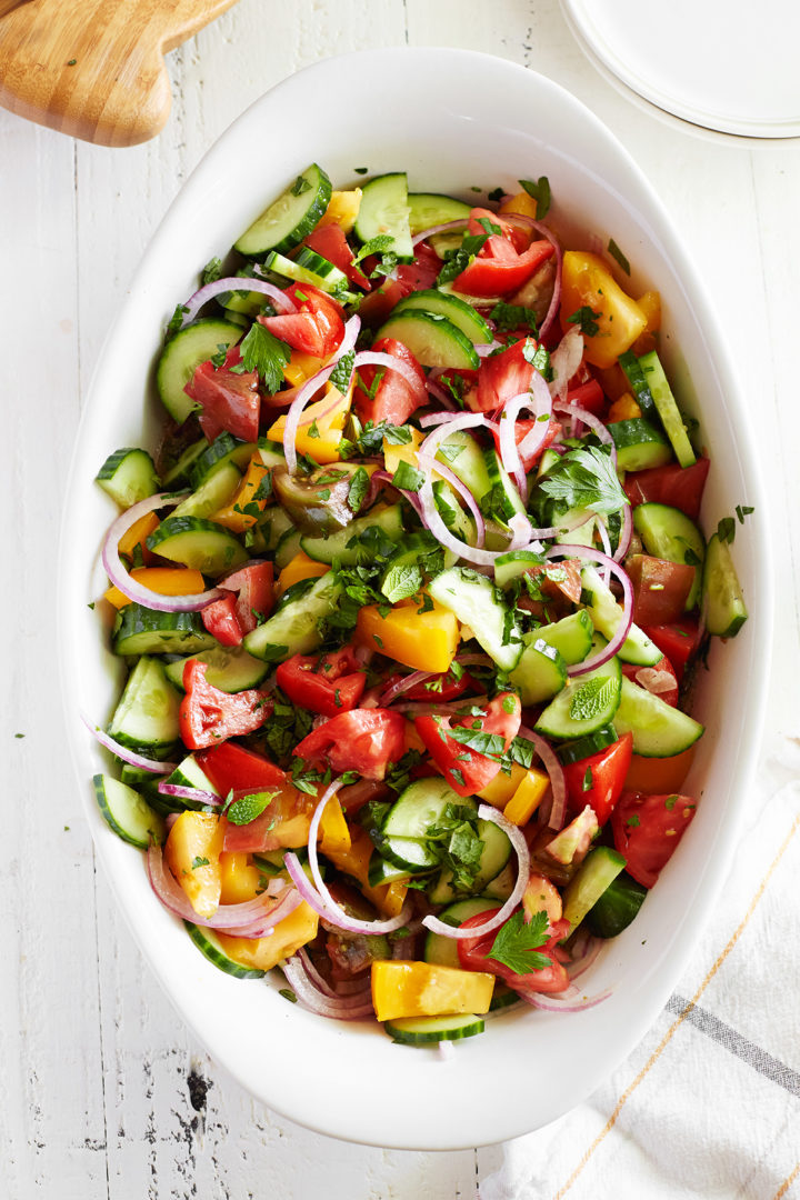 cucumber salad with tomatoes in a white serving dish