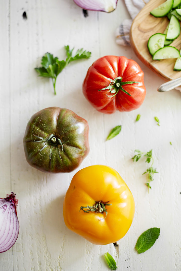 ingredients to make cucumber tomato onion salad arranged on a white table