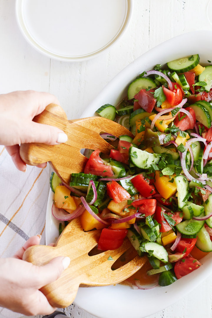 woman stirring onion cucumber tomato vinegar salad