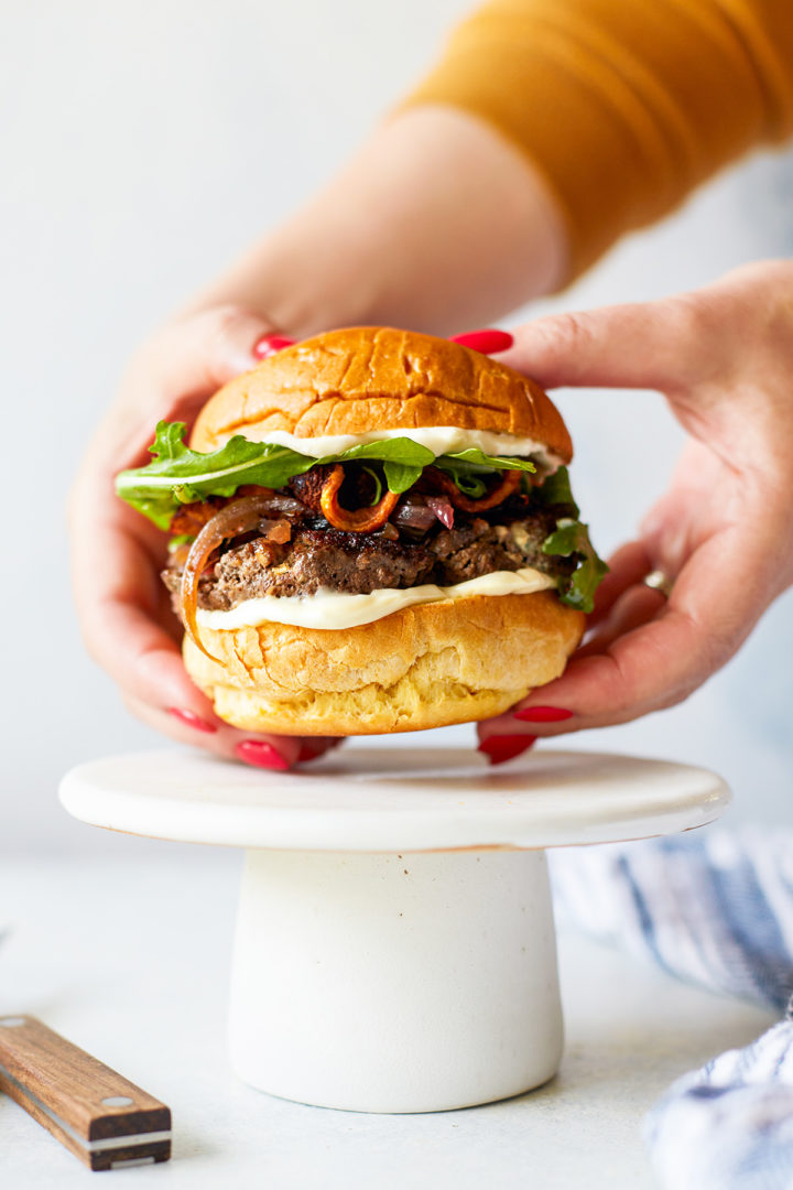 woman holding a bacon and blue cheese stuffed burger