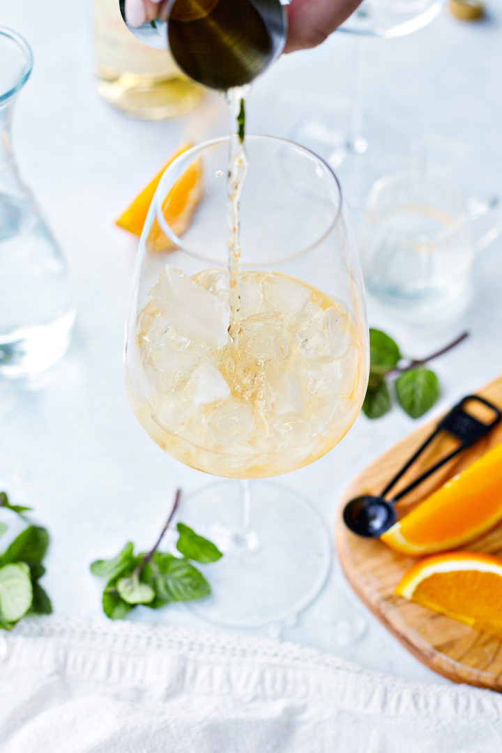 pouring lillet blanc into a spritzer glass