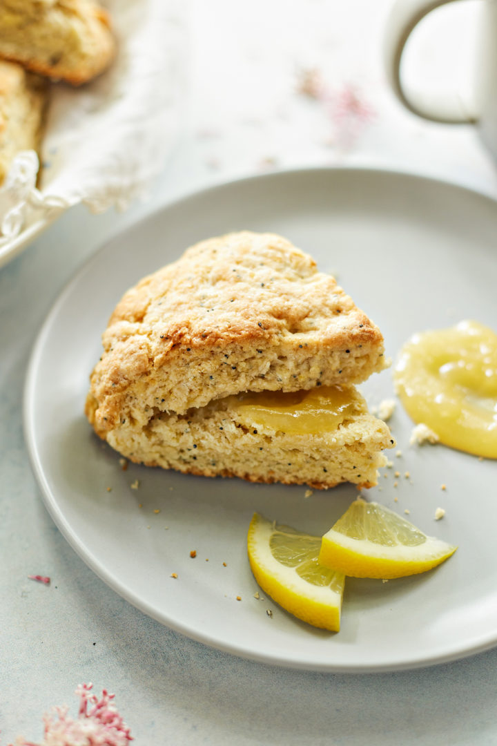 a sliced lemon poppyseed scone with lemon curd on a grey plate