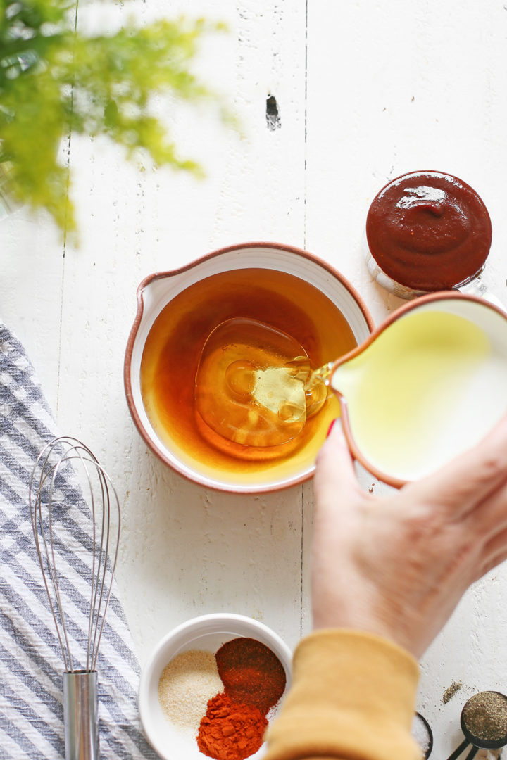 woman adding oil to a bowl