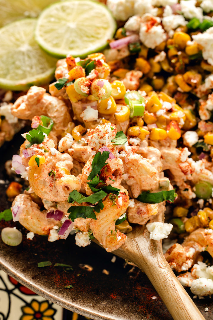 wooden spoon stirring a bowl of charred corn pasta salad