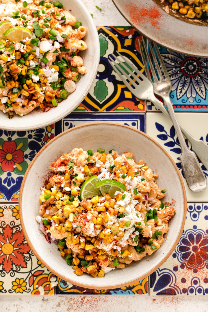 overhead photo of two bowls of mexican corn pasta salad on a tile table