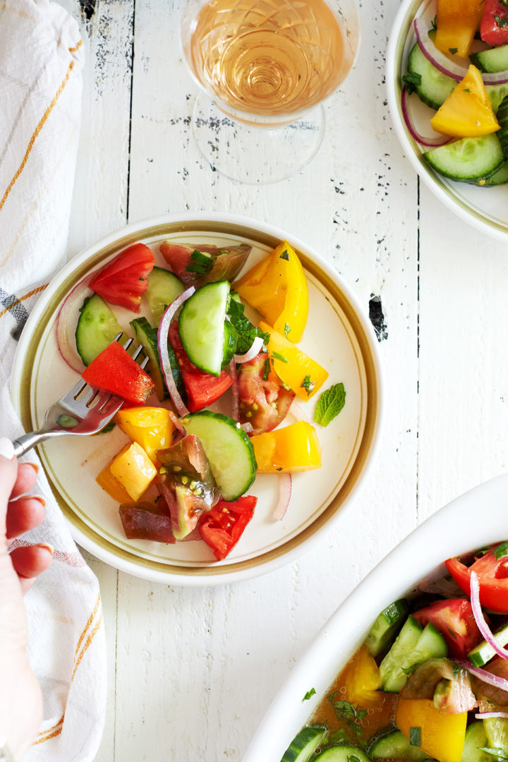 woman eating a plate of tomato cucumber salad