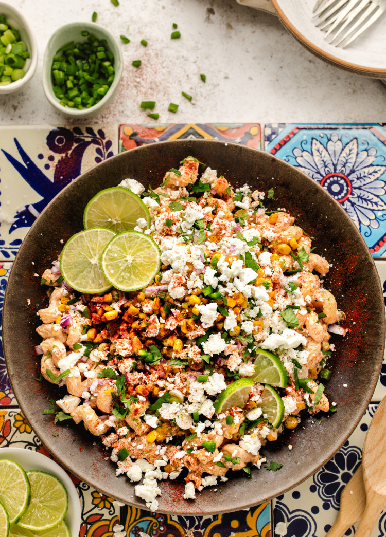 overhead photo of a bowl of Mexican street corn pasta salad garnished with lime slices