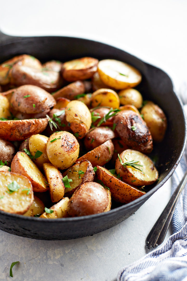 close up of traeger potatoes in a cast iron pan garnished with fresh herbs