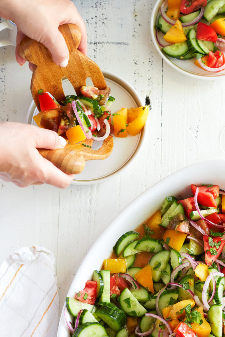 woman serving cucumber tomato onion salad