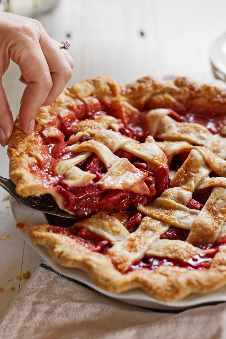 woman serving a strawberry rhubarb pie