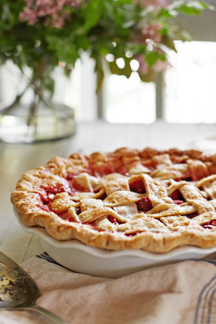 the best strawberry rhubarb pie on a white kitchen table in front of a window