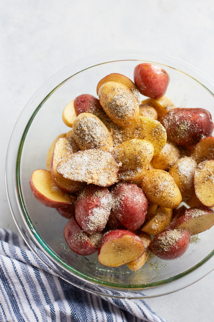 potatoes coated in ghee and seasonings in a glass bowl