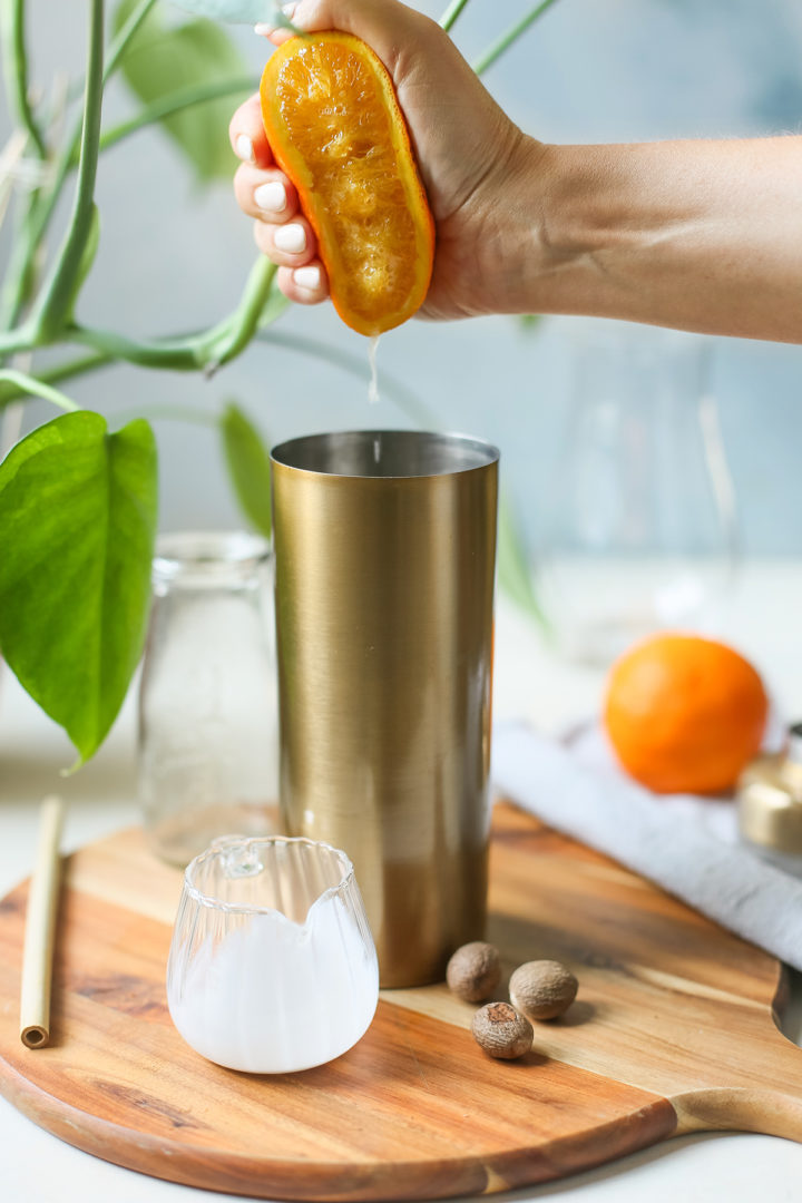 woman squeezing orange juice into a cocktail shaker