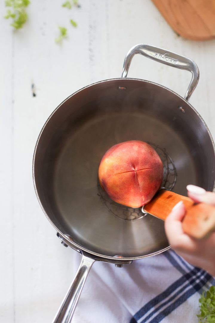 woman adding peaches to a pot of boiling water to blanch