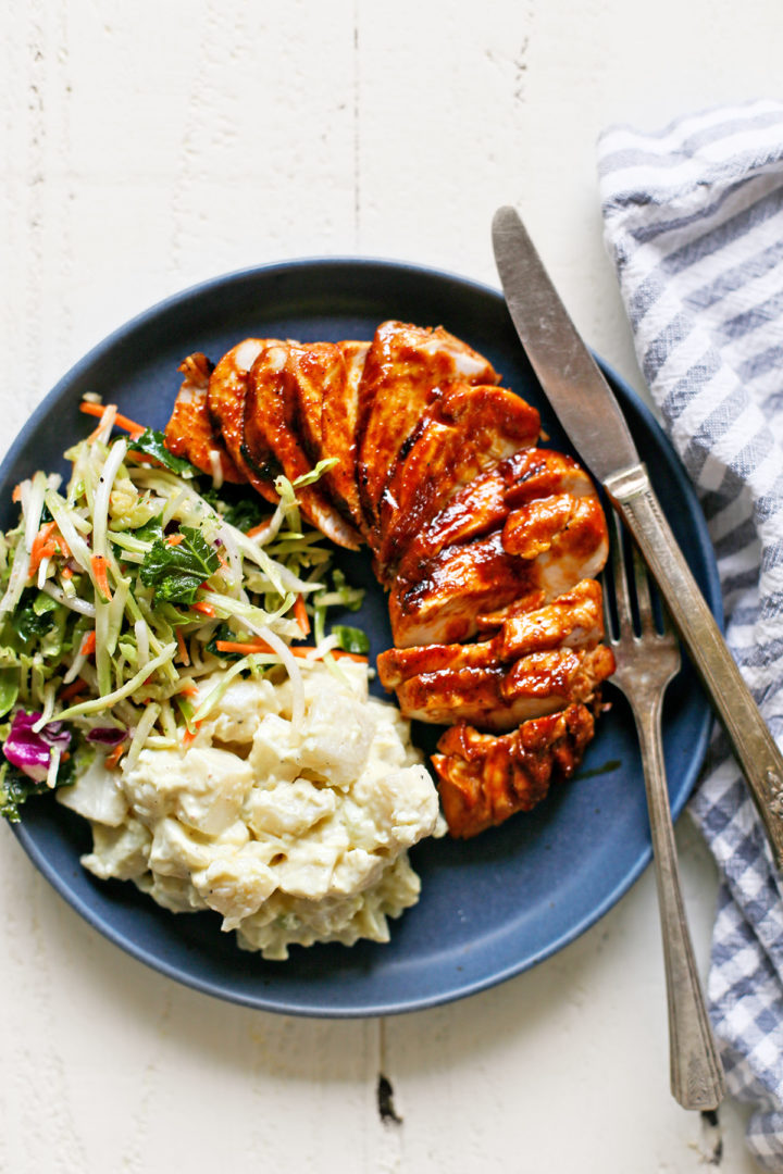 blue plate with sliced grilled bbq chicken and side dishes