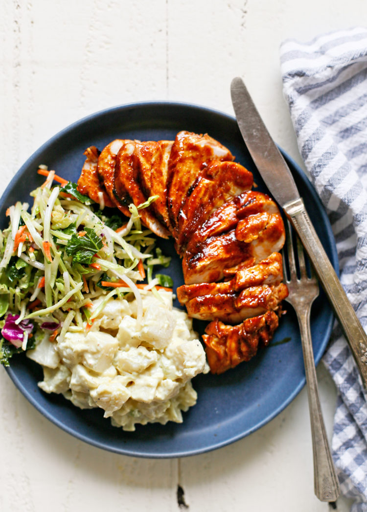 a blue plate with grilled bbq chicken and side dishes