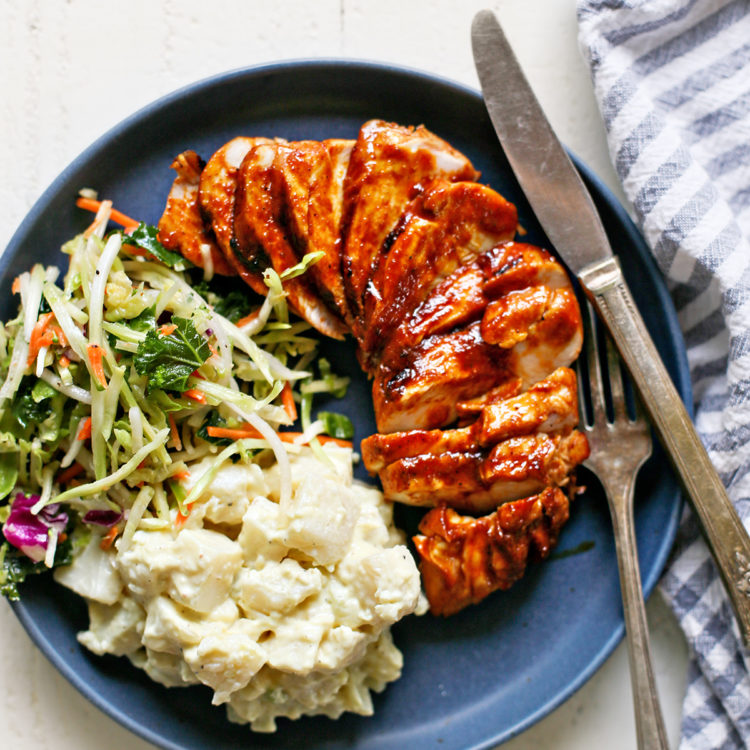 a blue plate with grilled bbq chicken and side dishes