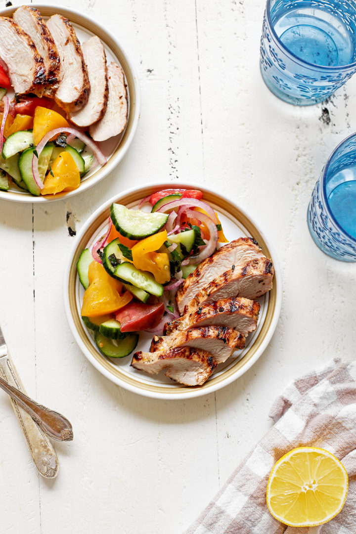 a plate with sliced grilled lemon rosemary chicken and salad