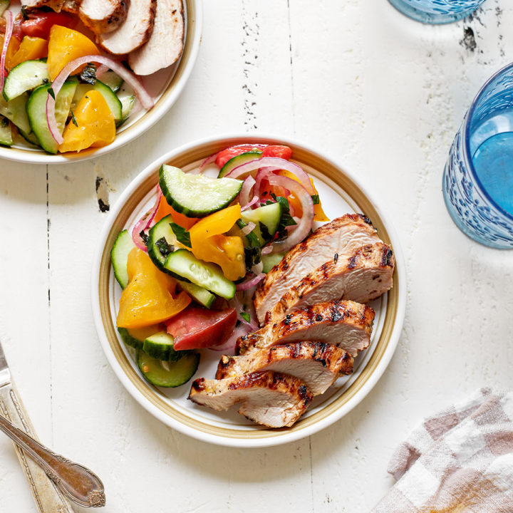 overhead photo of two plates of sliced lemon rosemary chicken served with salad