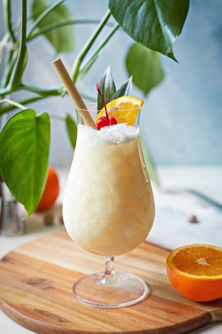 painkiller cocktail in a glass garnished with orange and cherry