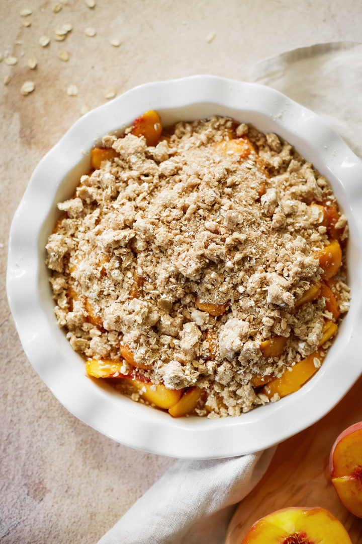 peach crisp with oatmeal in a baking dish before going into the oven