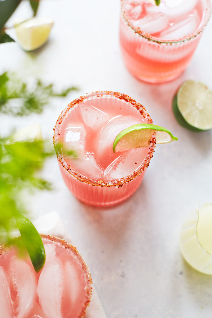 overhead photo of three glasses of watermelon margarita with a spicy salt rim and lime garnishes