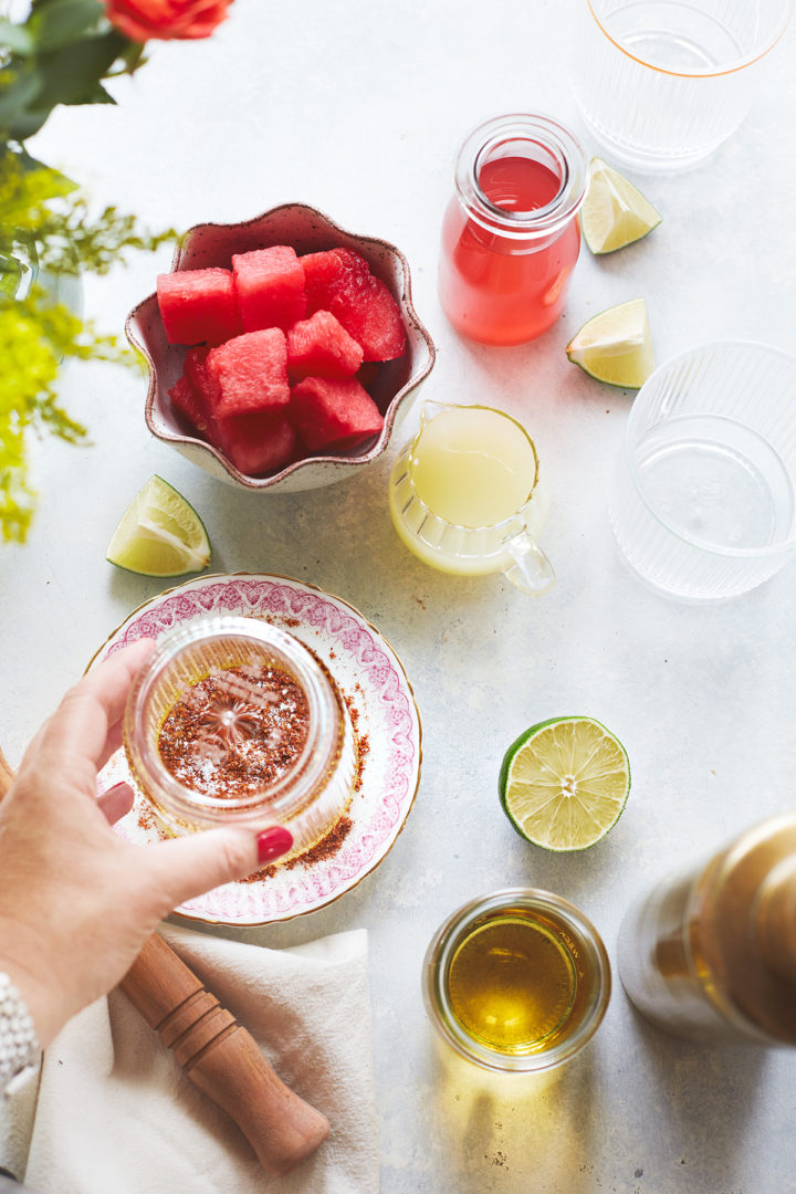 woman rimming a glass with spicy salt for a watermelon margarita recipe