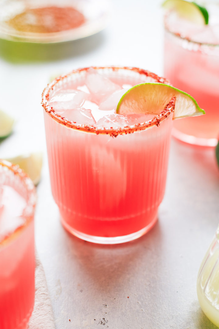 close up of a glass of watermelon margarita with lime garnish