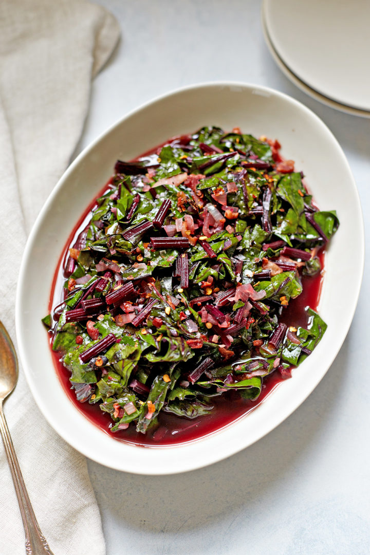 a serving dish of beet greens on a table