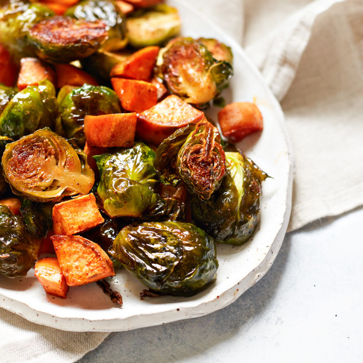 roasted brussels sprouts and sweet potatoes on a white serving platter