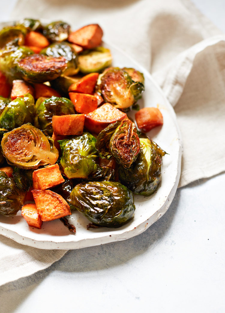 roasted brussels sprouts and sweet potatoes on a white serving platter