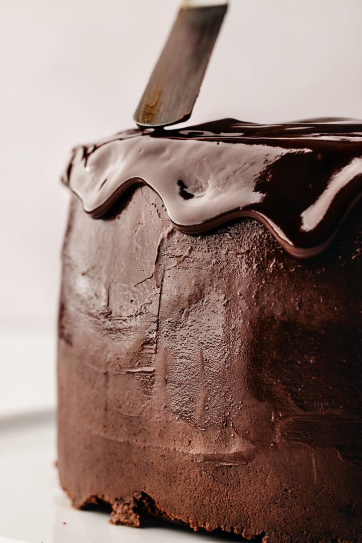 drizzling chocolate ganache onto a chocolate cake