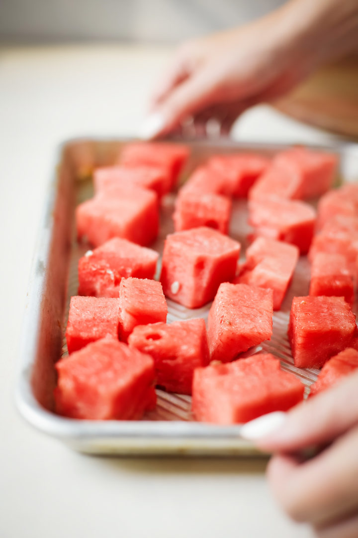 woman holding a tray with frozen watermelon chunks