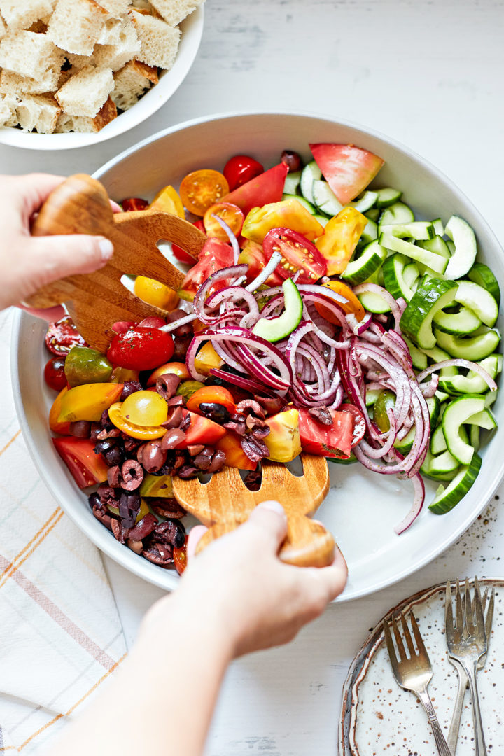 woman mixing vegetables for a summer panzanella recipe