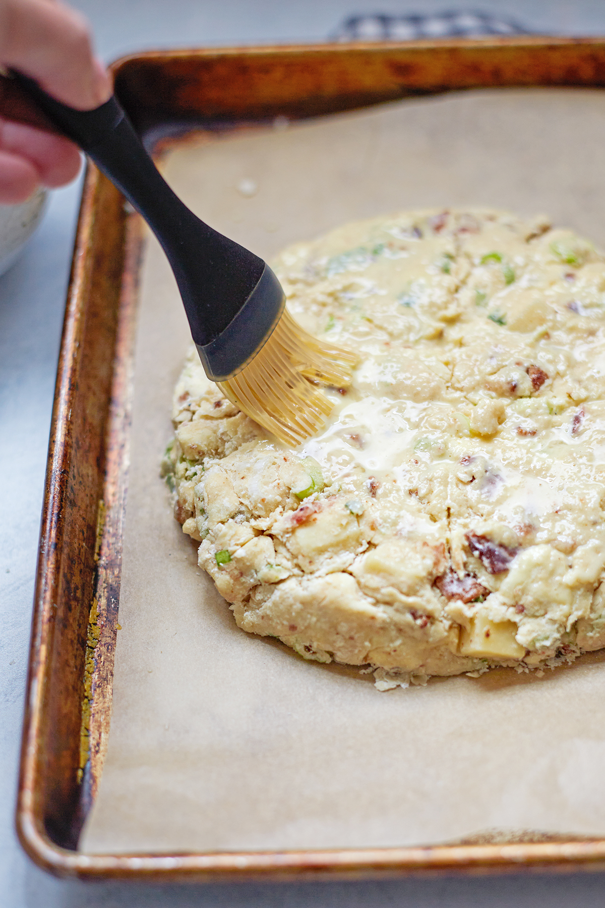 woman brushing egg wash on bacon and cheese scones