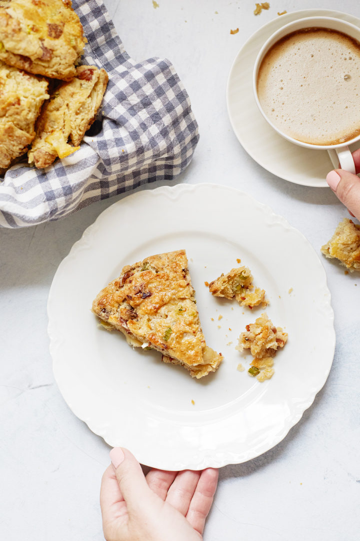 woman with a plate of cheese and bacon scone and cup of coffee