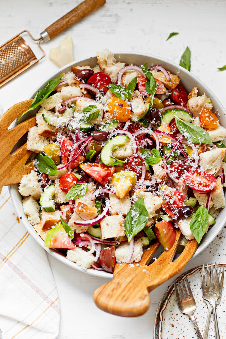 tomato panzanella in a white bowl with wooden salad tongs