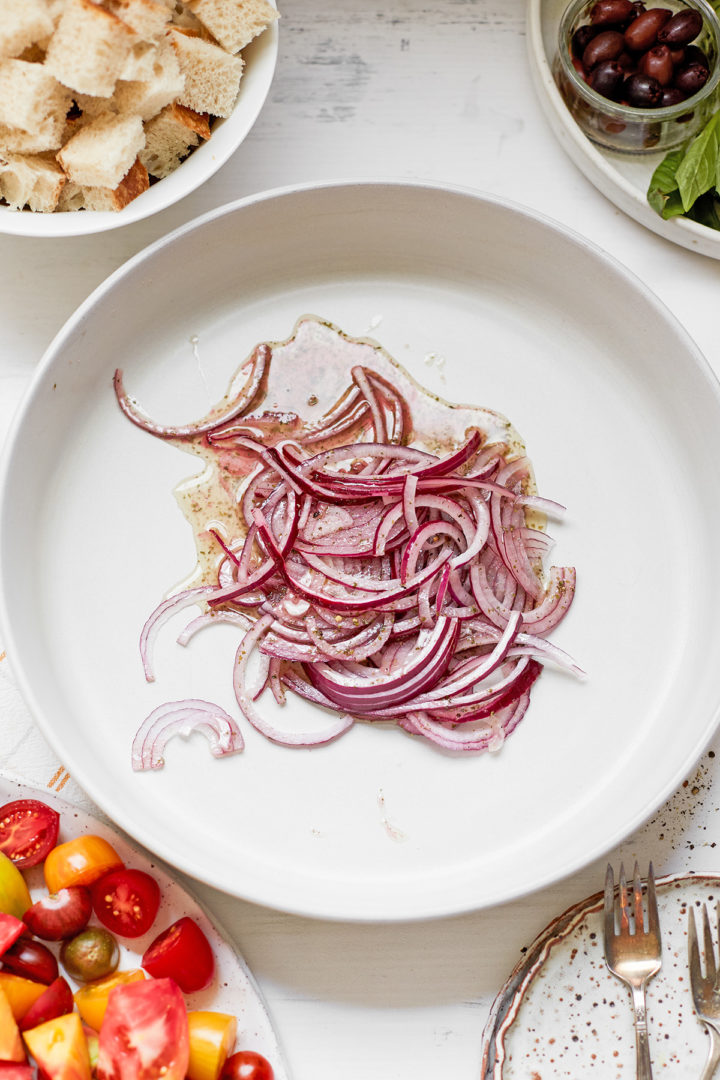 red onions in a white bowl with oil and vinegar