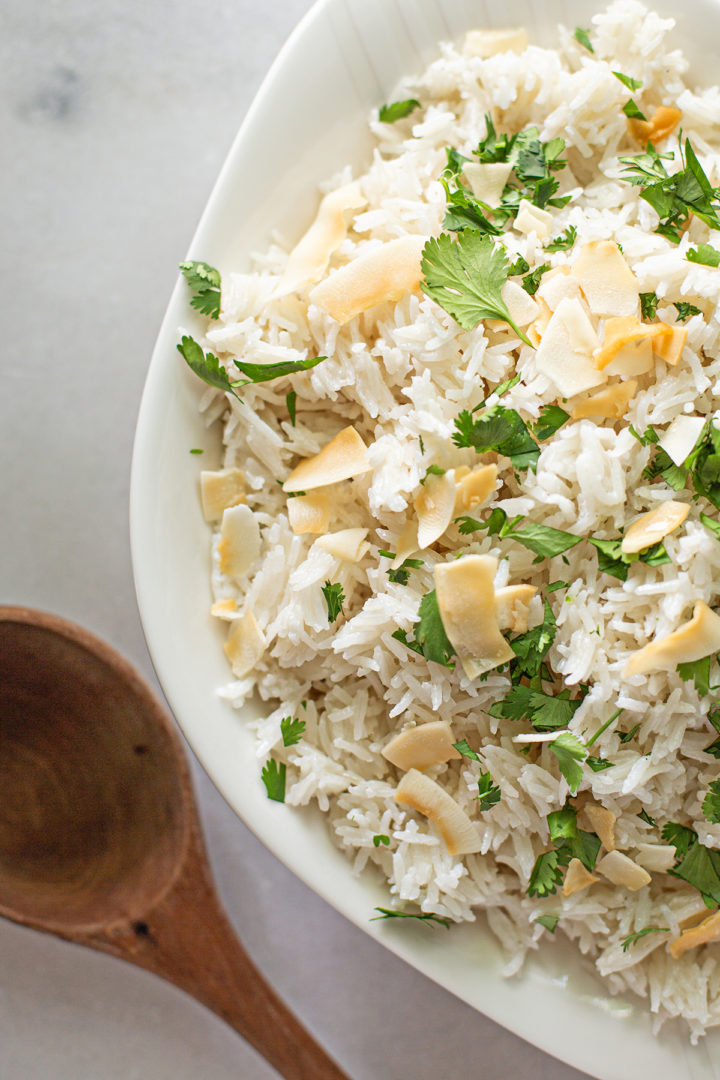 close up of coconut milk rice in a bowl with a wooden spoon