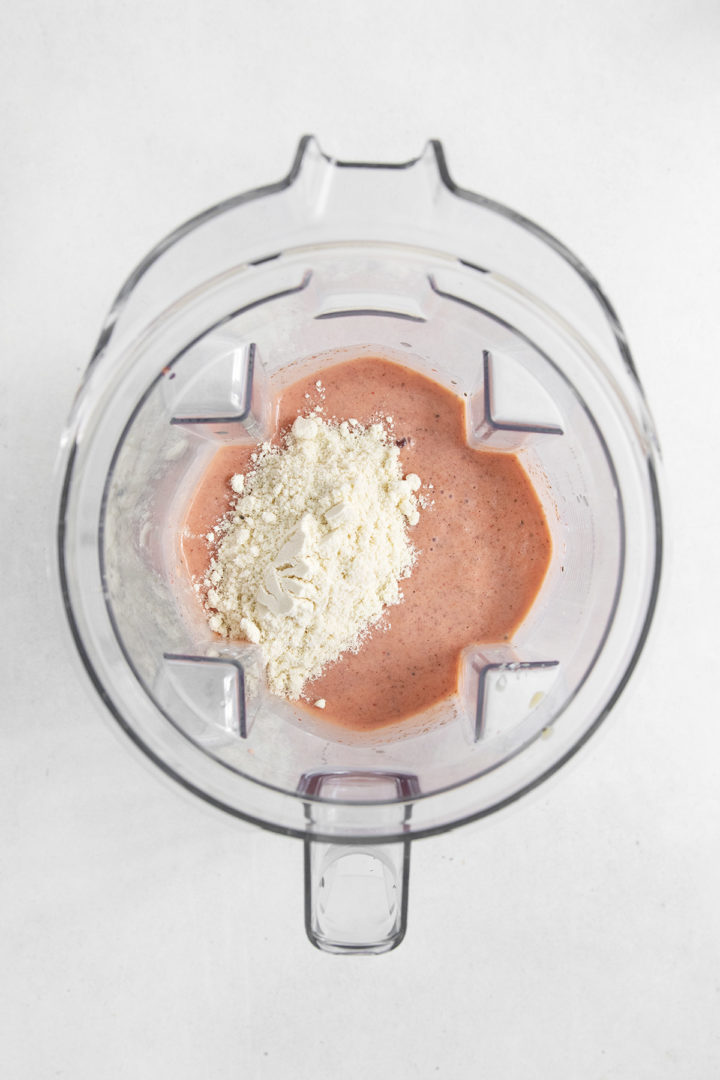 adding protein powder to the blender with the frozen passion fruit smoothie