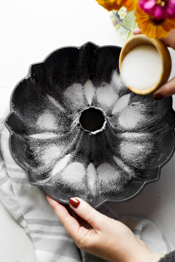 woman sprinkling sugar inside a greased bundt pan